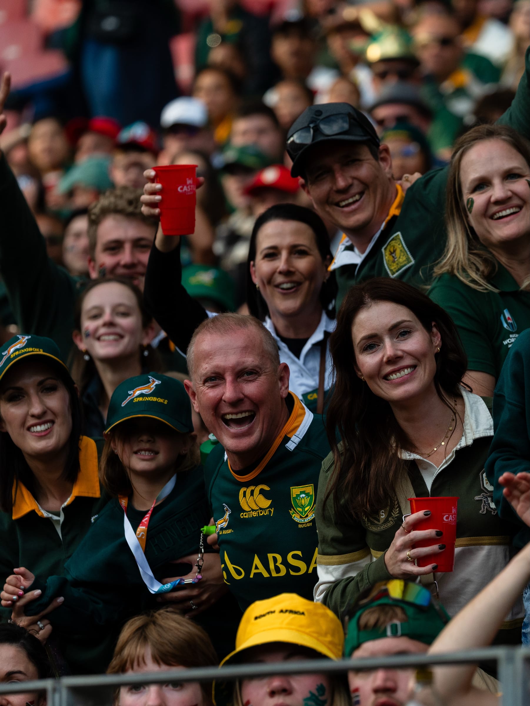 Group of Springboks supporters smiling together in the stands in green and gold