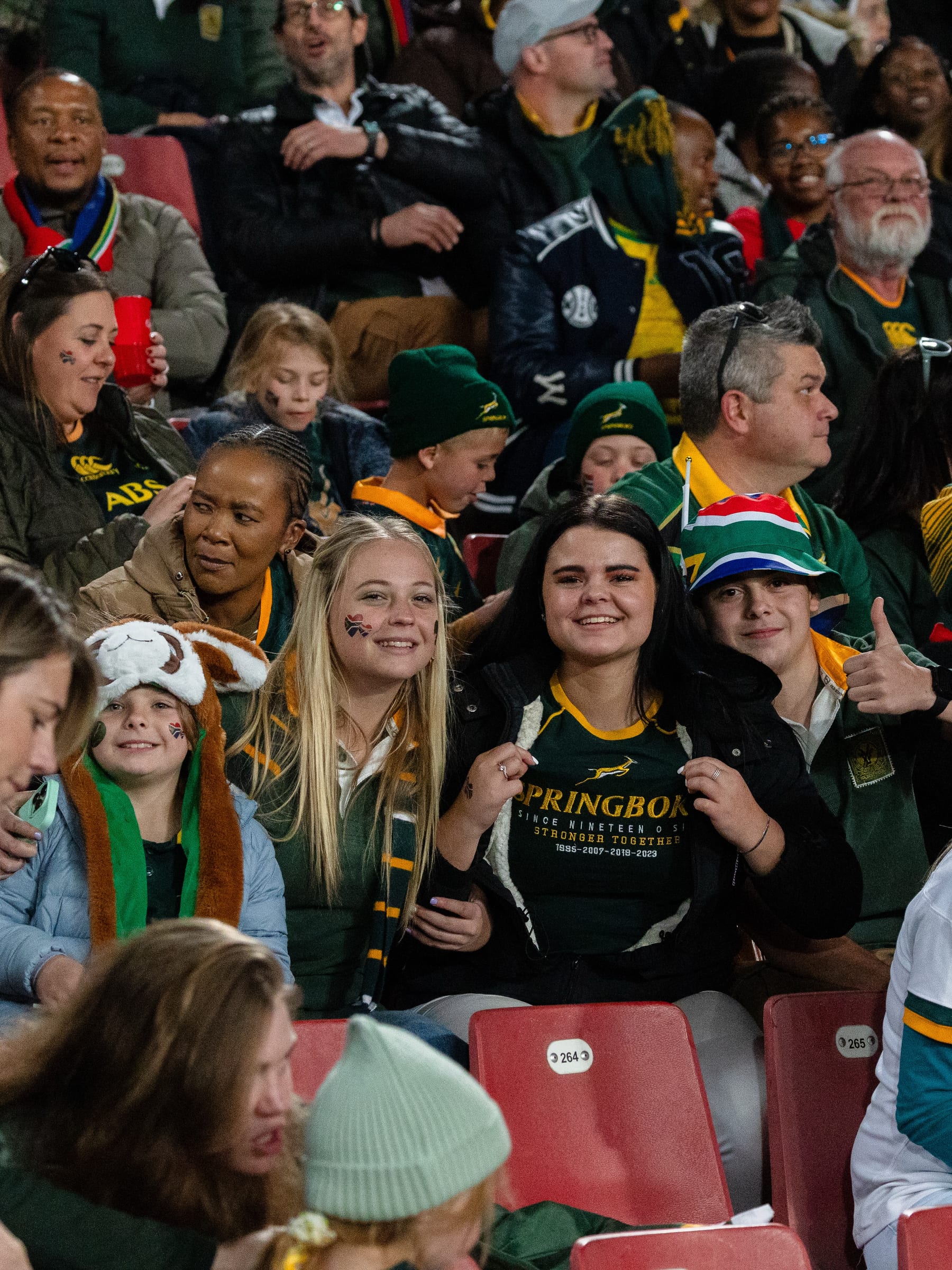 Families in the stands on match day, one holding a Springboks banner