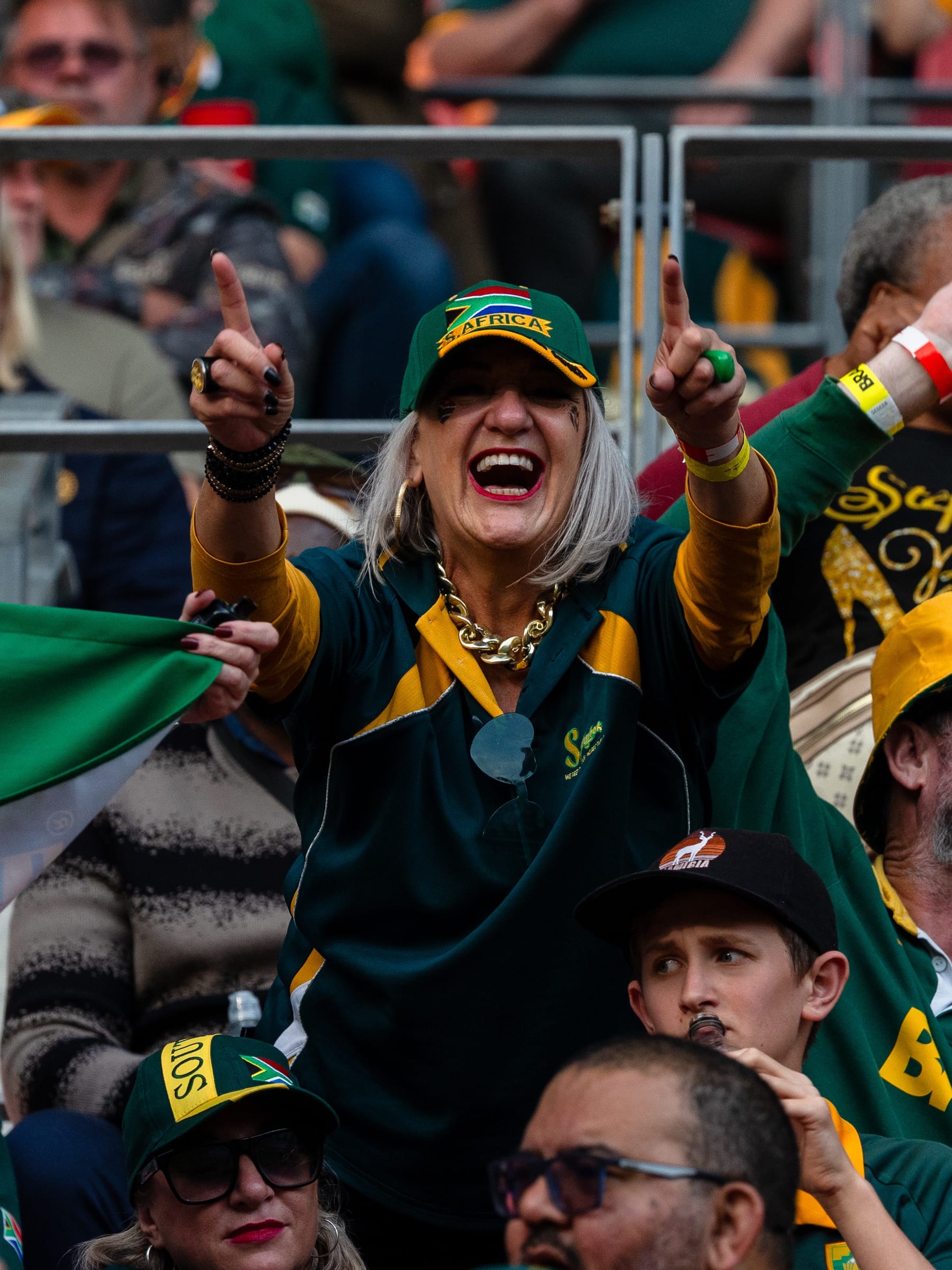 Supporter in a Springboks jersey and cap cheering with both hands raised